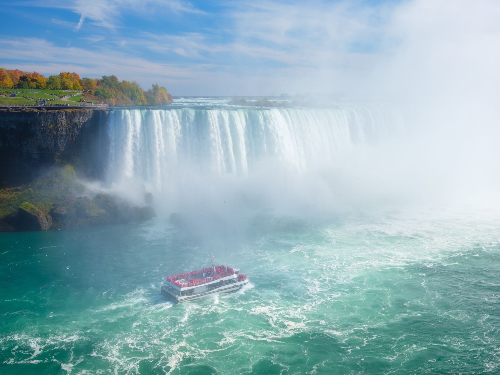 A tour boat in the churning water at the foot of the falls, wrapped in mist
